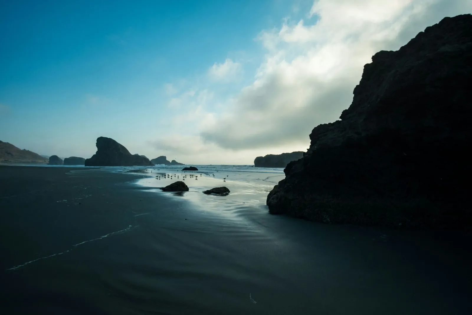 Black rock formations in the sea under blue sky at Gold Beach, Oregon.